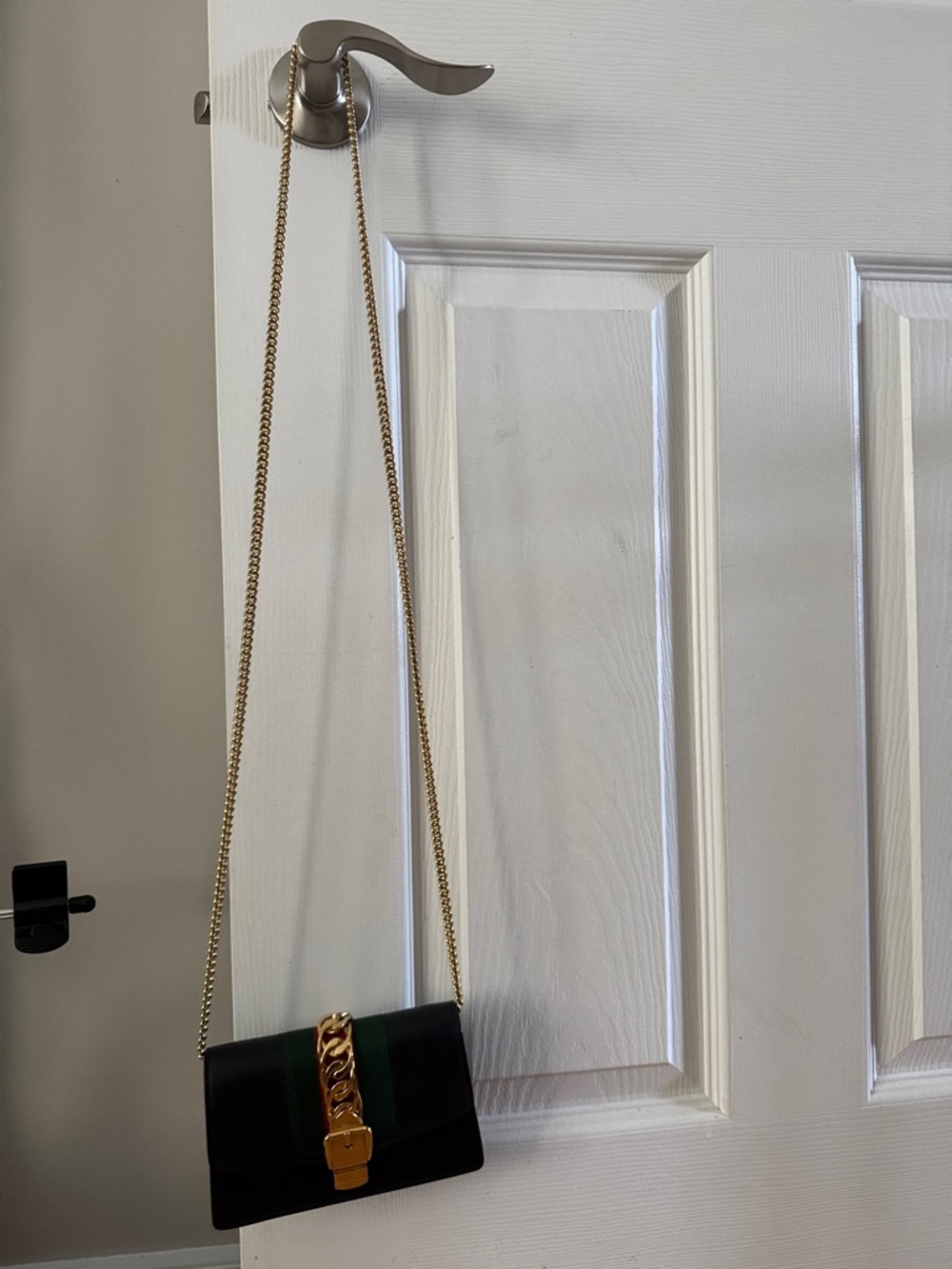 Black Crossbody Bag with Gold Chain Accent and Green Stripe